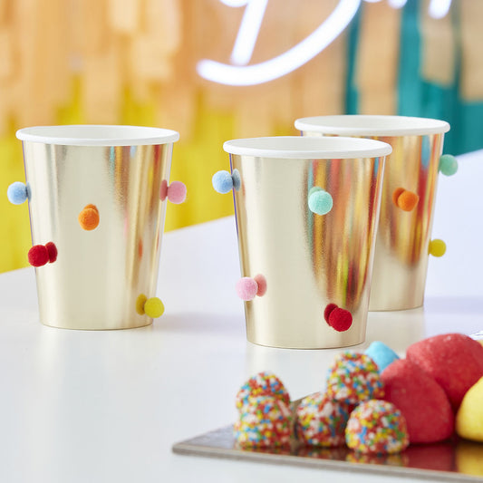 Golden birthday party cups and multicolored pompoms