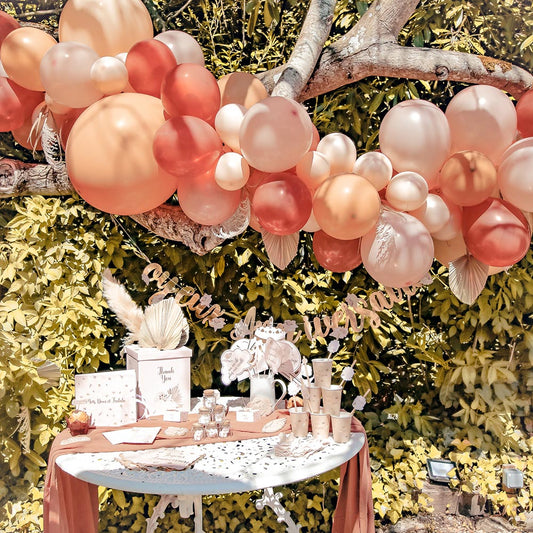 Decorazione di compleanno all'aperto: arco di palloncini e tavolo di pampa color ocra