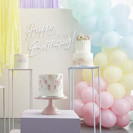 Pastel birthday decoration with arch of pastel balloons and wall of crepe ribbons