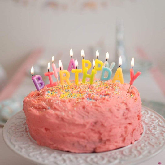 Torta di compleanno rosa e candele di buon compleanno multicolori pastello