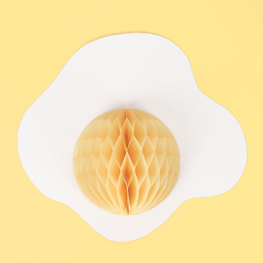 Inspiración en la decoración de la fiesta de la yema de huevo con una bola de nido de abeja de papel amarillo