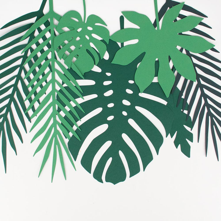 Decoración de cumpleaños tropical con hojas de papel tropical verde.