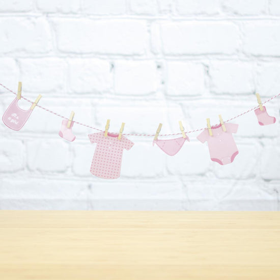 Guirlande avec vetements bébés roses pour deco gender reveal fille