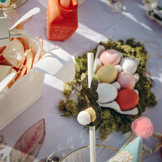 Mesa de pascua con pajitas de conejo dorado y huevos pastel
