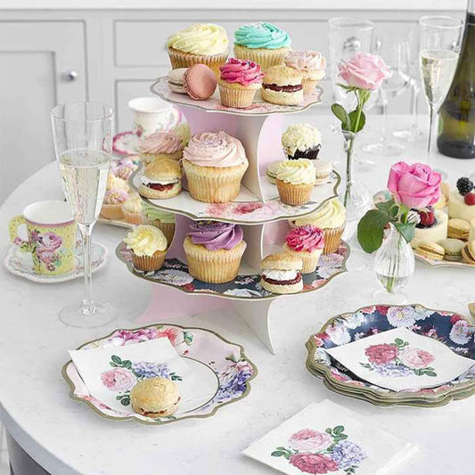 Decoración de mesa inglesa con puesto de tartas y vajilla de flores.